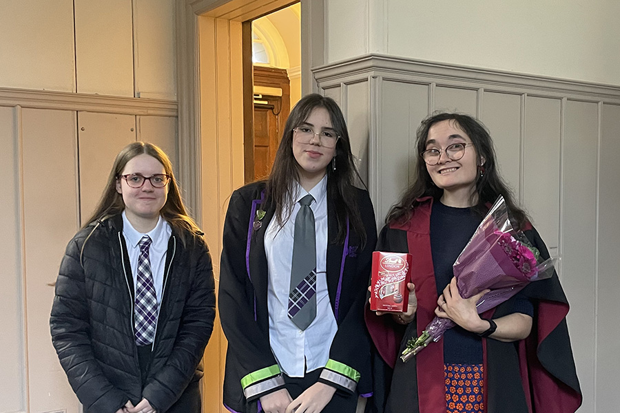 Two pupils presenting Anna Coopey with flowers