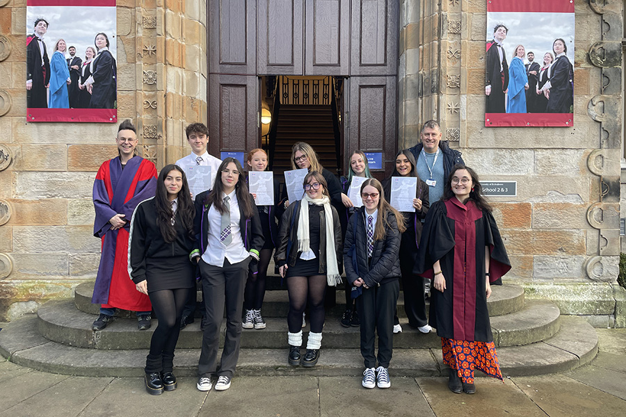 Students holding their certificates and standing with Henry Stead, Anna Coopey outside lower college hall